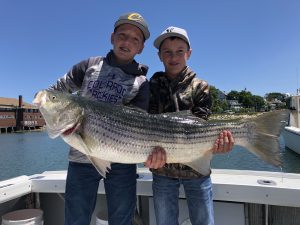 Two kids with a big striped bass