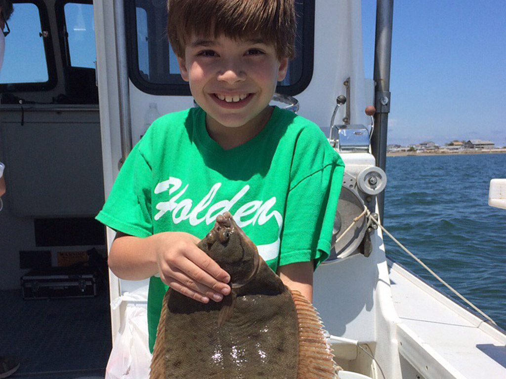 Kid smiling while holding his first flounder